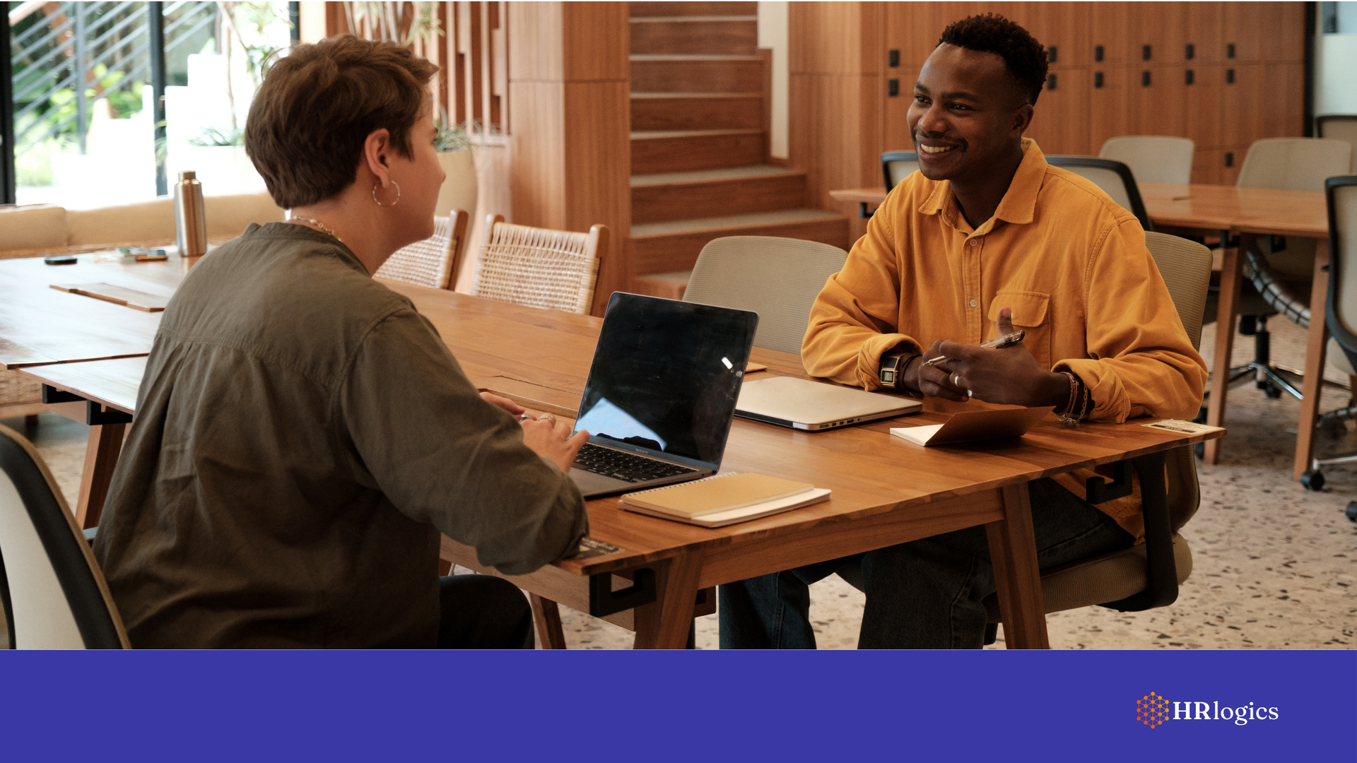 A recruiter interviewing a candidate in a modern office, with documents on screen suggesting a digital process.