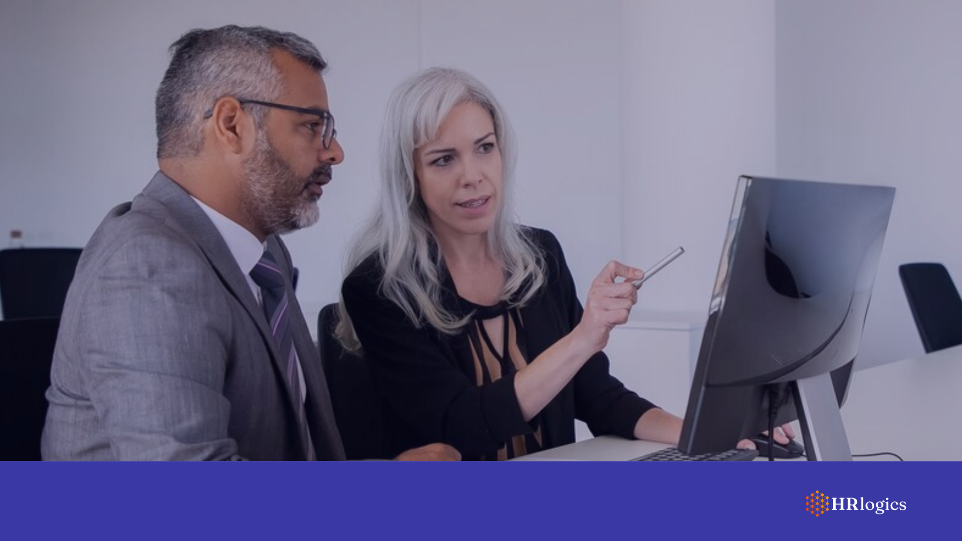 Two professionals collaborating while looking at a computer screen in a modern office setting.